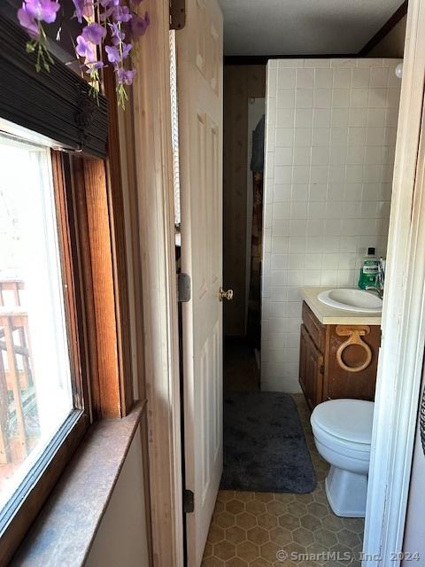 bathroom featuring tile patterned floors, vanity, toilet, and tile walls