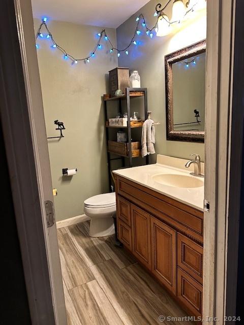 bathroom with wood-type flooring, vanity, and toilet