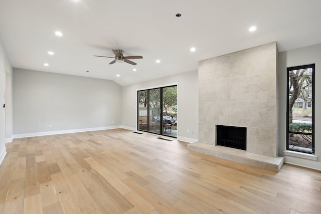 unfurnished living room featuring ceiling fan, a large fireplace, and light hardwood / wood-style flooring