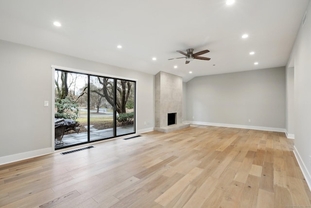 unfurnished living room with lofted ceiling, a fireplace, light hardwood / wood-style floors, and ceiling fan