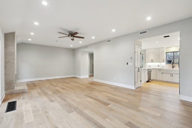 unfurnished living room with ceiling fan, sink, and light wood-type flooring