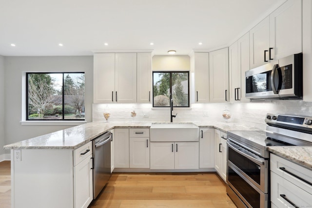 kitchen featuring white cabinetry, light stone countertops, appliances with stainless steel finishes, and sink