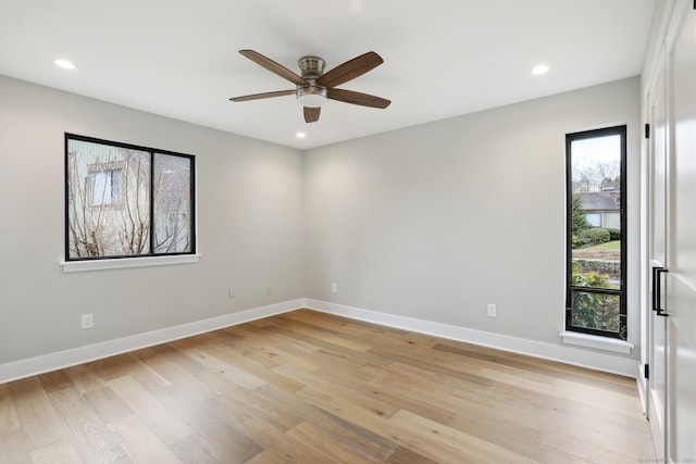 empty room featuring ceiling fan, a wealth of natural light, and light hardwood / wood-style floors