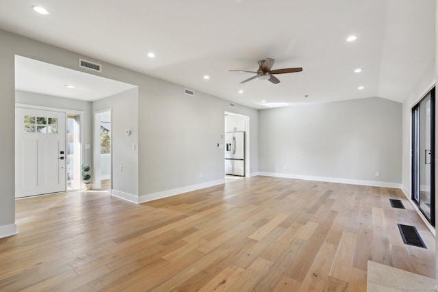 unfurnished living room with ceiling fan, lofted ceiling, and light wood-type flooring