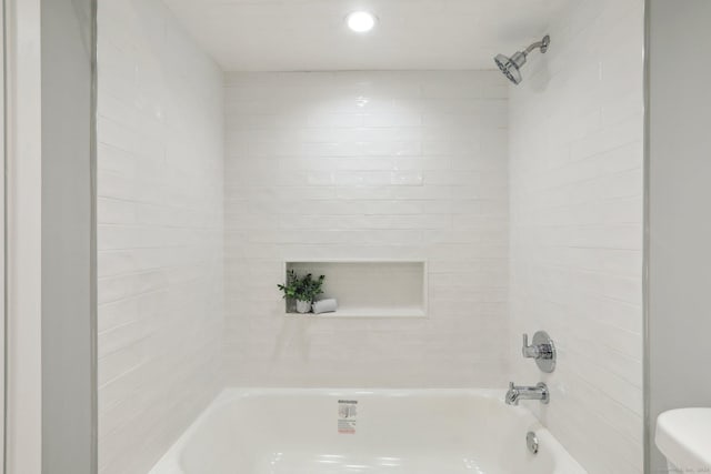 bathroom featuring tiled shower / bath combo and toilet