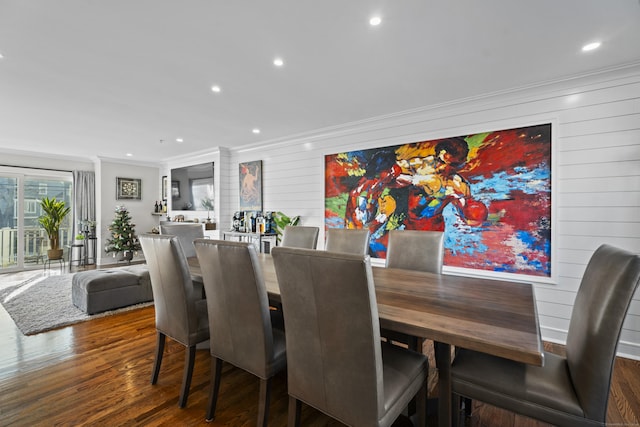 dining space featuring crown molding, dark wood-type flooring, and wood walls