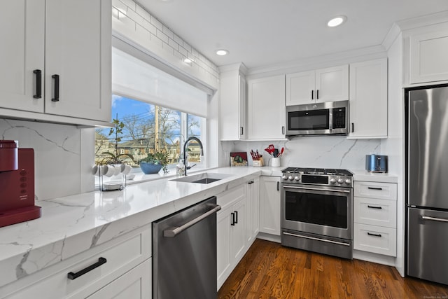 kitchen featuring backsplash, sink, light stone counters, white cabinetry, and stainless steel appliances