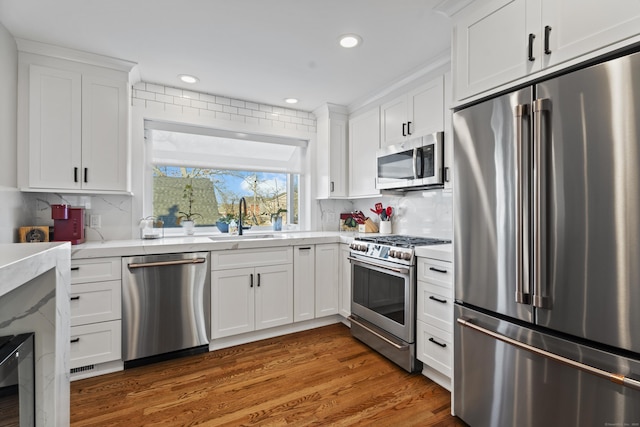 kitchen with white cabinets, backsplash, high quality appliances, and sink