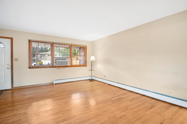 spare room featuring cooling unit, baseboard heating, and light hardwood / wood-style flooring