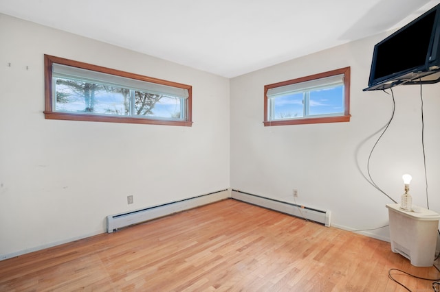 spare room featuring hardwood / wood-style floors, a healthy amount of sunlight, and baseboard heating