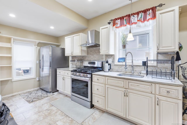 kitchen featuring backsplash, wall chimney exhaust hood, stainless steel appliances, sink, and decorative light fixtures