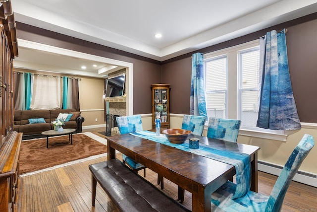 dining room with hardwood / wood-style floors, baseboard heating, and a tray ceiling