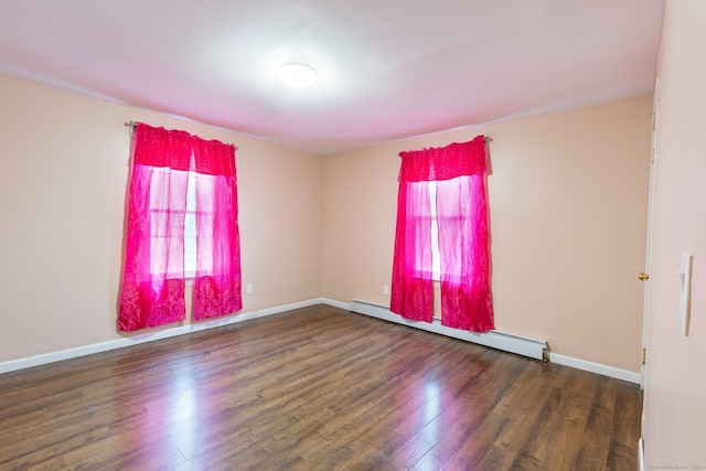 spare room featuring baseboard heating and dark wood-type flooring