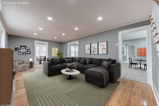 living room with light wood-type flooring and ornamental molding