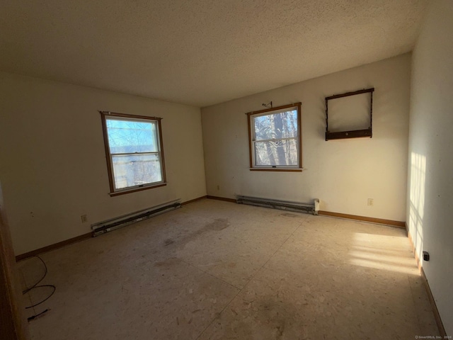 empty room featuring plenty of natural light, a baseboard radiator, and a textured ceiling