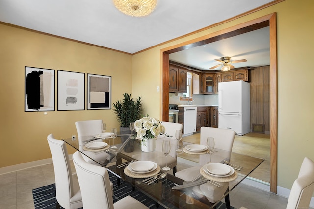 tiled dining room with ceiling fan, sink, and crown molding