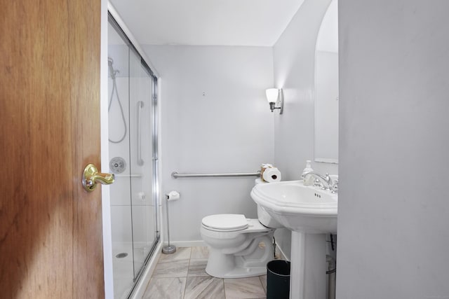 bathroom featuring a shower with door and toilet