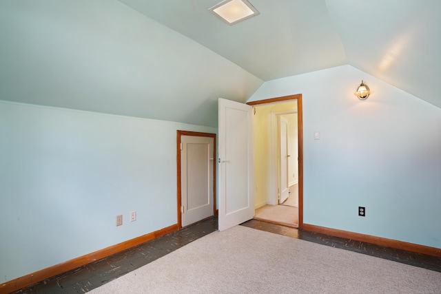 bonus room with dark carpet and vaulted ceiling