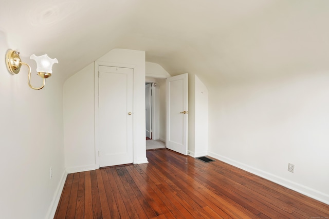 additional living space featuring dark wood-type flooring and vaulted ceiling