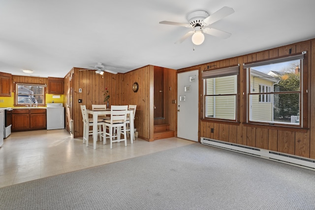 unfurnished dining area featuring ceiling fan, washer / dryer, wooden walls, and a baseboard heating unit