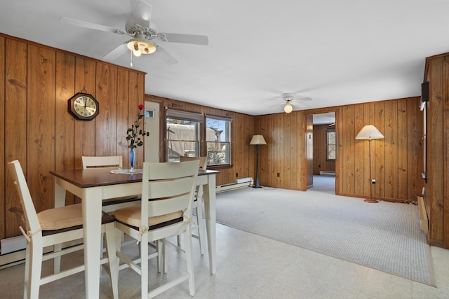 dining room with ceiling fan, wood walls, light carpet, and a baseboard radiator