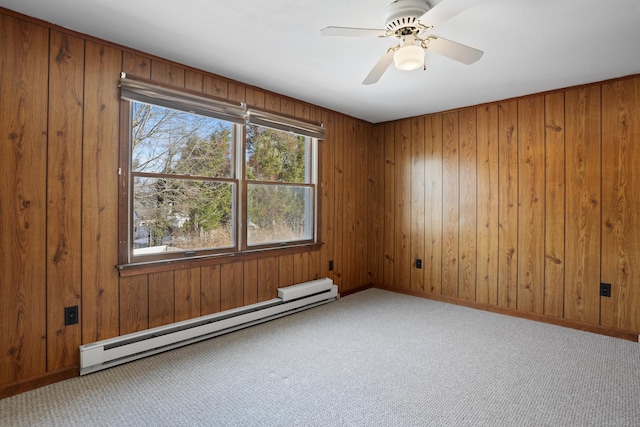 carpeted empty room with ceiling fan, wooden walls, and a baseboard radiator