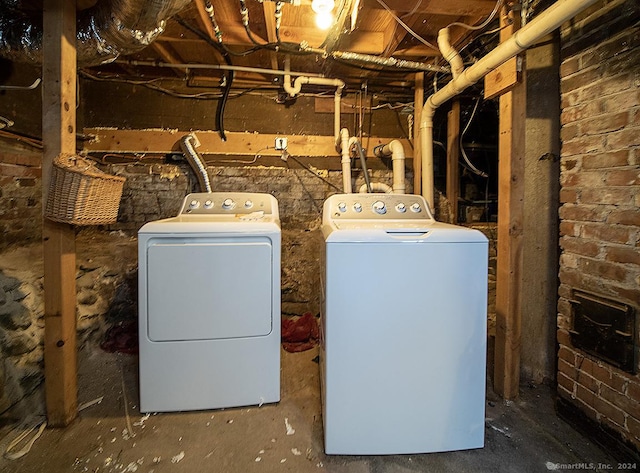 washroom with washer and clothes dryer and brick wall