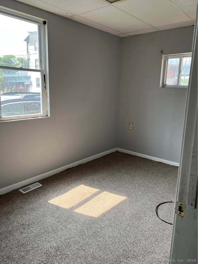 carpeted spare room featuring a paneled ceiling and plenty of natural light