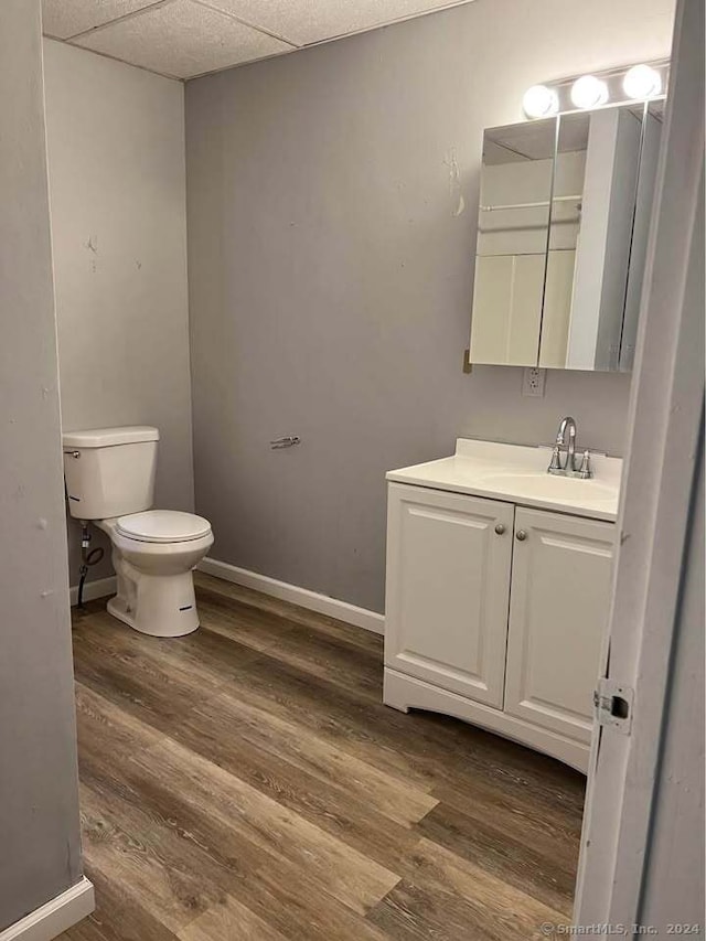 bathroom featuring hardwood / wood-style floors, vanity, toilet, and a drop ceiling