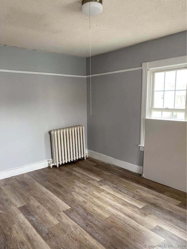 unfurnished room featuring radiator heating unit, a textured ceiling, and hardwood / wood-style flooring