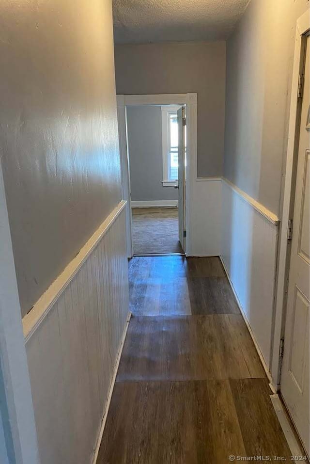 corridor with dark hardwood / wood-style flooring and a textured ceiling