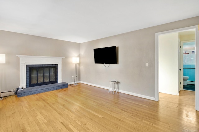 unfurnished living room featuring light wood-type flooring, a fireplace, and baseboard heating