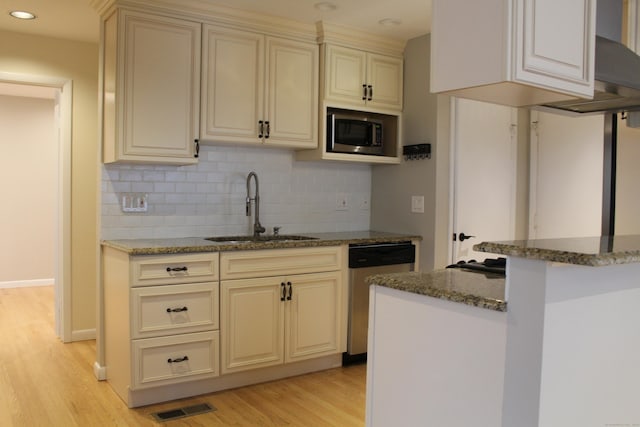 kitchen featuring built in microwave, dishwasher, sink, light hardwood / wood-style floors, and cream cabinetry