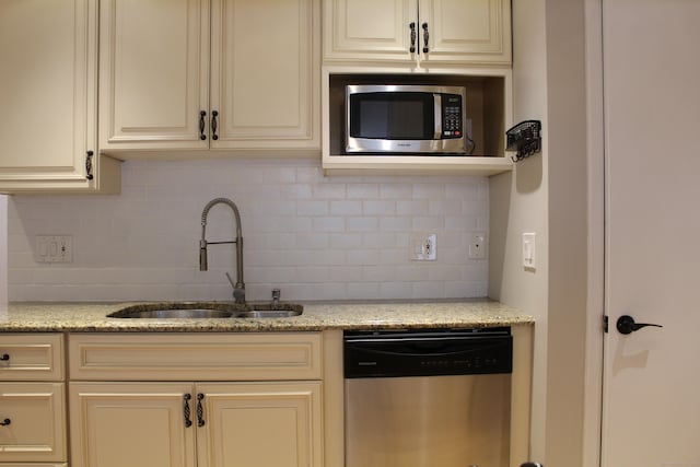 kitchen featuring backsplash, light stone countertops, sink, and appliances with stainless steel finishes