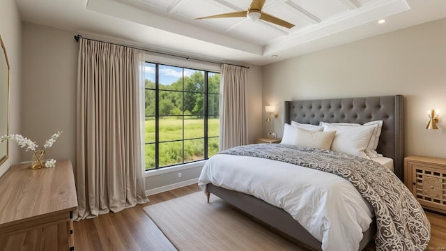 bedroom featuring coffered ceiling, ceiling fan, wood-type flooring, and a tray ceiling