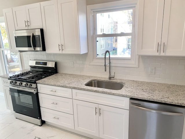 kitchen featuring white cabinets, sink, light stone countertops, and stainless steel appliances