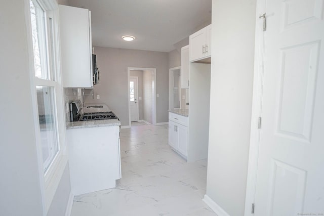 kitchen featuring light stone countertops, white cabinetry, and range