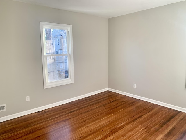 empty room featuring dark wood-type flooring and a healthy amount of sunlight