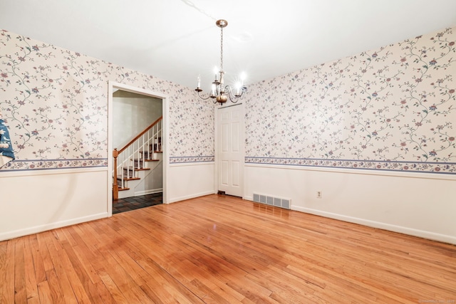 empty room featuring an inviting chandelier and hardwood / wood-style floors