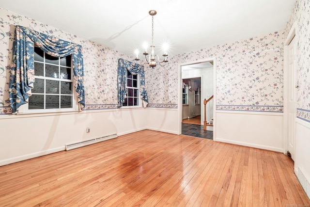 unfurnished dining area featuring baseboard heating, a chandelier, and hardwood / wood-style flooring