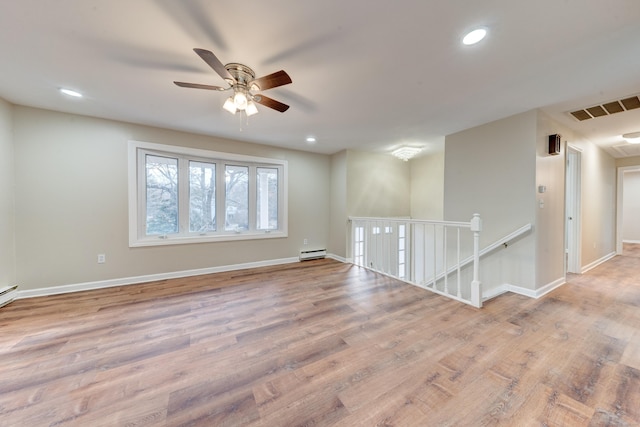 empty room featuring ceiling fan, light hardwood / wood-style floors, and a baseboard heating unit