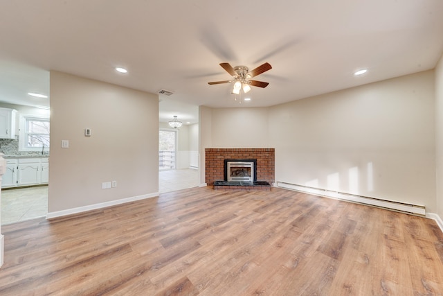 unfurnished living room featuring a fireplace, light wood-type flooring, a baseboard radiator, and ceiling fan