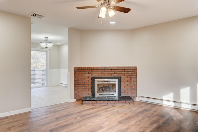 unfurnished living room with a fireplace, baseboard heating, ceiling fan with notable chandelier, and light hardwood / wood-style flooring