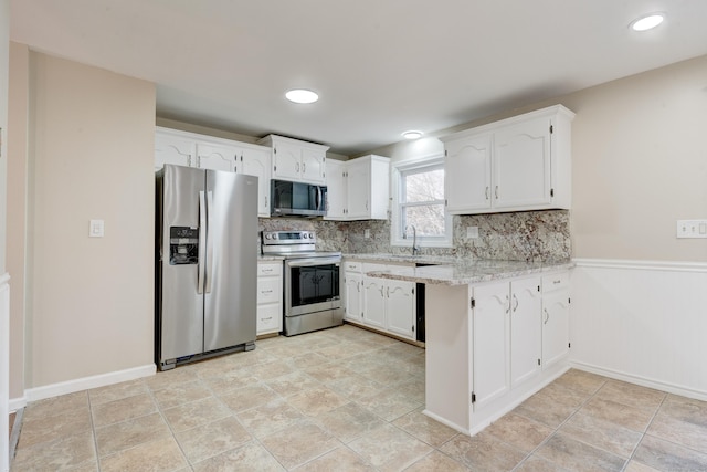 kitchen featuring light stone countertops, sink, tasteful backsplash, white cabinets, and appliances with stainless steel finishes