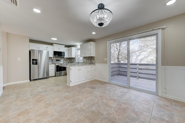 kitchen with backsplash, stainless steel appliances, decorative light fixtures, white cabinets, and a chandelier