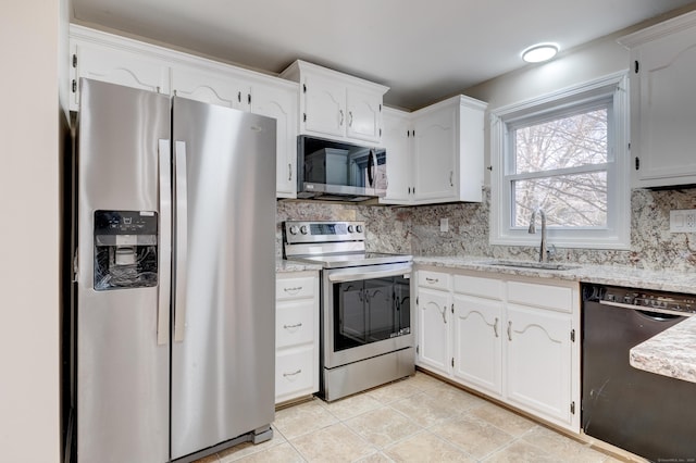 kitchen with sink, light tile patterned flooring, backsplash, white cabinets, and appliances with stainless steel finishes