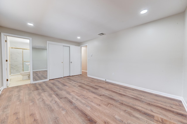 unfurnished bedroom featuring light hardwood / wood-style floors, a closet, and ensuite bath