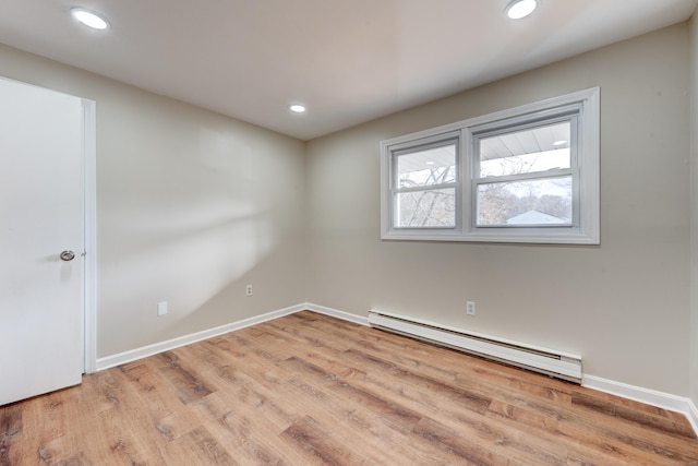 empty room featuring baseboard heating and light hardwood / wood-style flooring