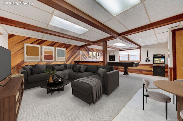 living room with a drop ceiling, wood walls, and pool table