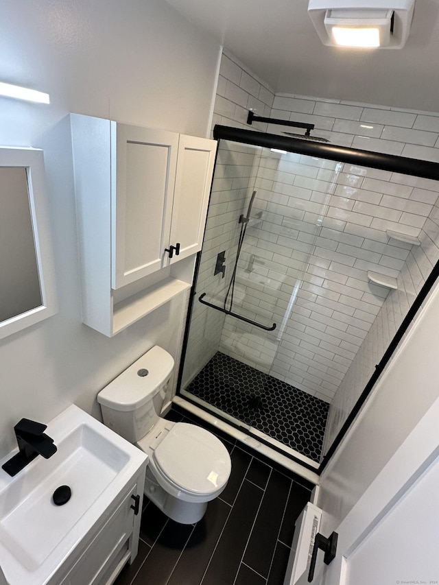 bathroom featuring vanity, toilet, and a shower with door